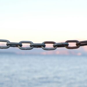 A chain hanging in front of the sea at sunset